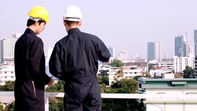 工程师和工人站在建筑工地上，看着将要建造的建筑蓝图，并指着将要建造的建筑的位置。视频素材