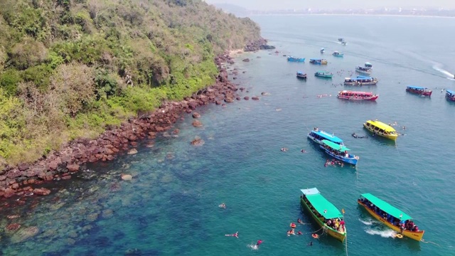 在印度南果阿海滩游泳的人周围漂浮在海洋上的船，鸟瞰图视频素材