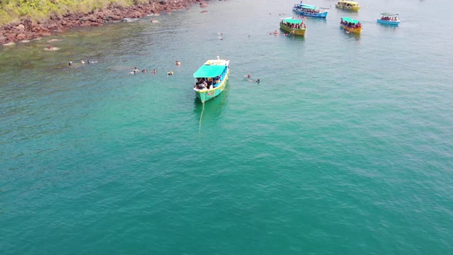 在印度南果阿海滩游泳的人周围漂浮在海洋上的船，鸟瞰图视频素材