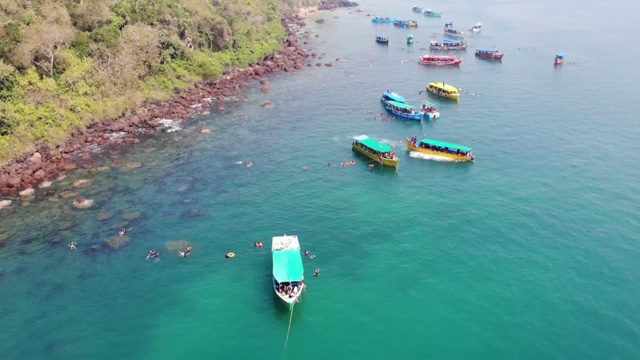 在印度南果阿海滩游泳的人周围漂浮在海洋上的船，鸟瞰图视频素材