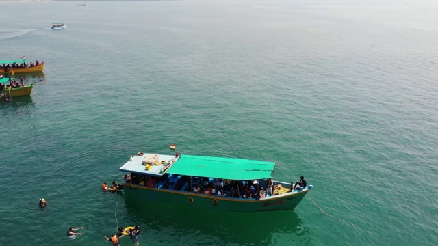 在印度南果阿海滩游泳的人周围漂浮在海洋上的船，鸟瞰图视频素材