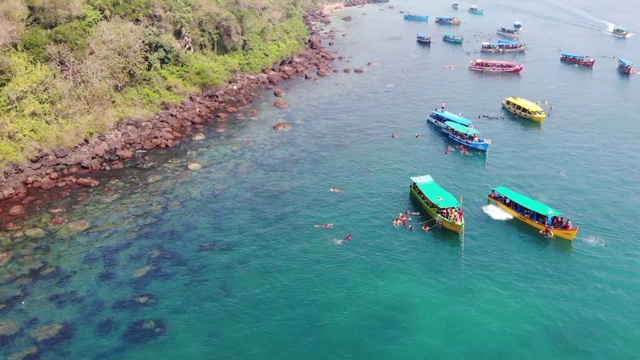 在印度南果阿海滩游泳的人周围漂浮在海洋上的船，鸟瞰图视频素材