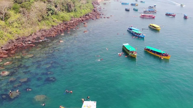 在印度南果阿海滩游泳的人周围漂浮在海洋上的船，鸟瞰图视频素材