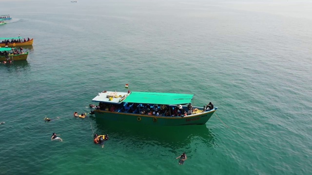 在印度南果阿海滩游泳的人周围漂浮在海洋上的船，鸟瞰图视频素材