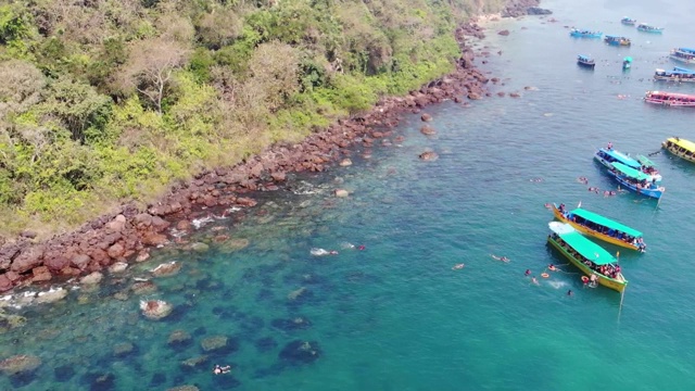 在印度南果阿海滩游泳的人周围漂浮在海洋上的船，鸟瞰图视频素材