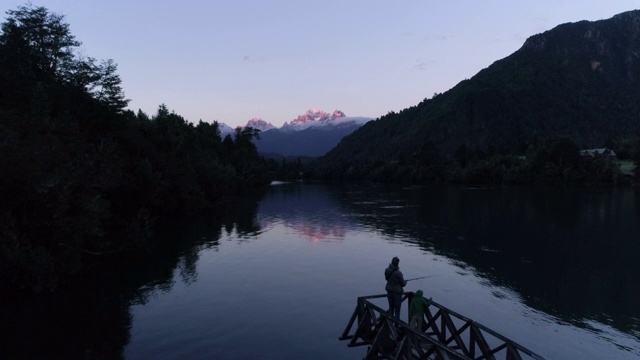 空中女子钓鱼在一个湖，森林和山日落视频素材