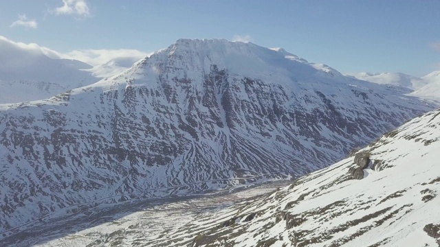 航拍，飞过冰雪覆盖的山脉，冰岛东部峡湾。冰岛乡村景观在春天或秋天的雪山季节之间。阳光明媚，适合旅游。视频素材