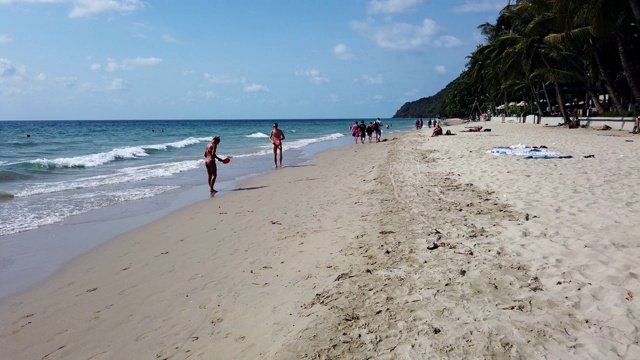 泰国Koh Chang - 2020年1月27日:在高昌岛的白色沙滩上，穿着泳衣的人们，穿着比基尼的妇女散步和日光浴的时间流逝。白云在蓝天上飞翔，棕榈树，夏天的时间视频素材