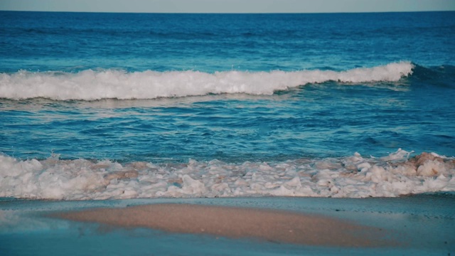 蓝绿色的海浪拍打着海滩视频素材