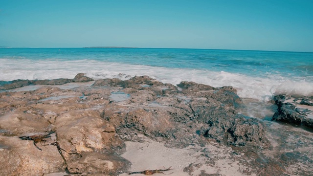 蓝色的海浪拍打着布满岩石的海滩视频素材