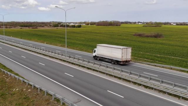 鸟瞰图货车。大型货车在移动。航拍美丽乡村公路上的卡车。春日油菜花田道路上半卡车鸟瞰图。视频素材