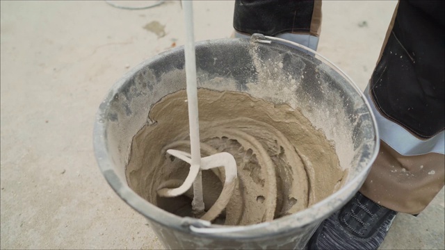 在桶里搅拌溶液。用电动搅拌机搅拌混凝土灰泥视频素材