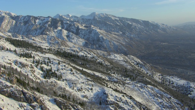 从奥林匹斯山的斜坡上鸟瞰积雪覆盖的瓦萨奇山脉，与遥远的杨木高地，美国犹他州。视频素材