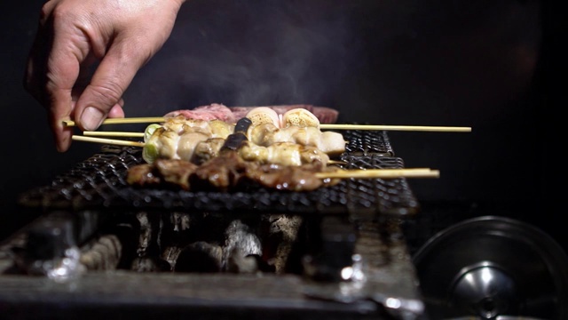 慢镜头小贩在夜市街头用钢烤架烹饪烤肉串。视频素材