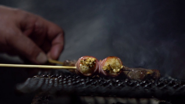 慢镜头小贩在夜市街头用钢烤架烹饪烤肉串。视频素材