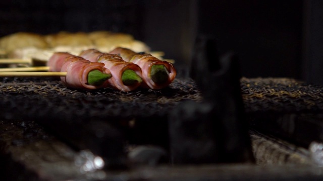 慢镜头小贩在夜市街头用钢烤架烹饪烤肉串。视频素材