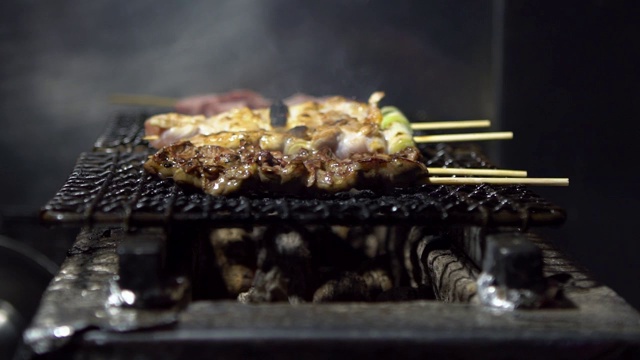 慢镜头小贩在夜市街头用钢烤架烹饪烤肉串。视频素材