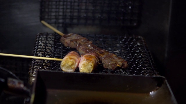 慢镜头小贩在夜市街头用钢烤架烹饪烤肉串。视频素材