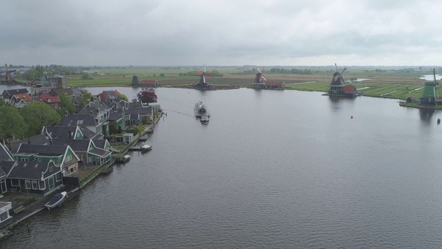 航拍荷兰北部的传统历史风车和小镇Zaanse Schans，荷兰河边有船驶近视频素材