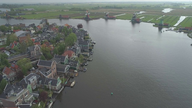 航拍荷兰北部的传统历史风车和小镇Zaanse Schans，以河流为背景视频素材