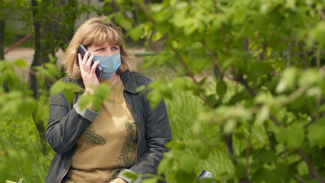 一位戴着医用口罩的年轻女子正在讲电话。视频素材