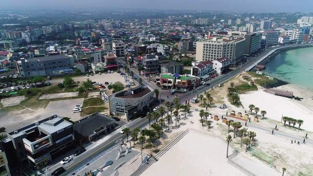 韩国济州岛济州市，咸德海滩附近的城市建筑和行驶在Johamhaean-ro路/ Jocheon-eup上的汽车视频素材