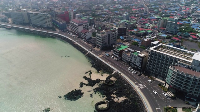 韩国济州岛济州市，咸德海滩附近的城市建筑和行驶在Johamhaean-ro路/ Jocheon-eup上的汽车视频素材