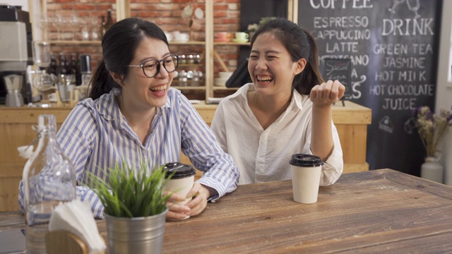 两个女朋友一起在咖啡店喝咖啡。上班前，女同事们坐在桌子前聊天和大笑。男侍者在咖啡厅里为顾客端羊角面包。视频素材