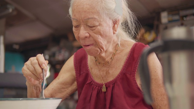 年长的亚洲女人在家吃饭。视频素材