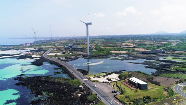 韩国济州岛济州岛，金宁沿海公路上行驶的汽车和风力发电机视频素材