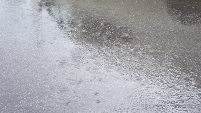 雨水滴进沥青路面上的水坑里视频素材