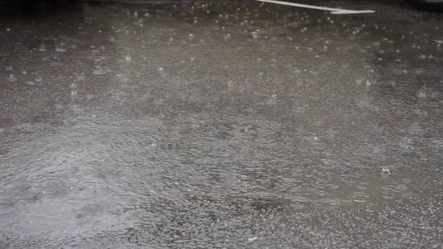 雨水滴进沥青路面上的水坑里视频素材