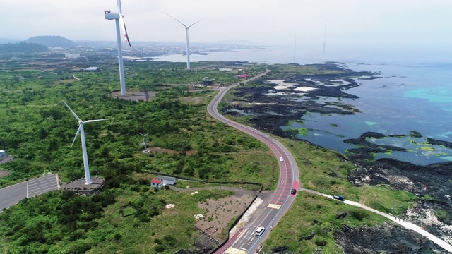 韩国济州岛济州岛，金宁沿海公路上行驶的汽车和风力发电机视频素材