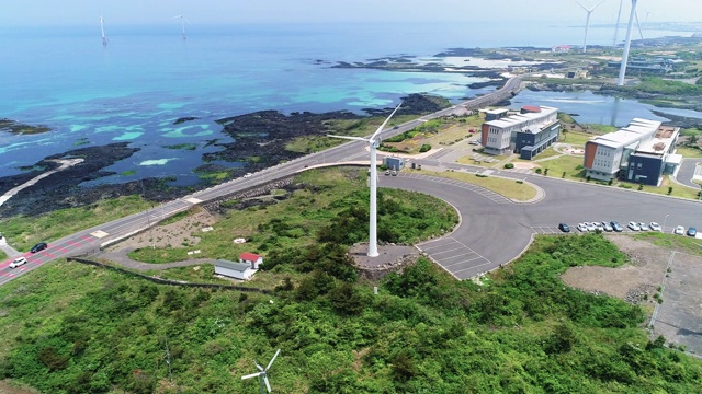 韩国济州岛济州岛，金宁沿海公路上行驶的汽车和风力发电机视频素材