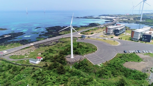 韩国济州岛济州岛，金宁沿海公路上行驶的汽车和风力发电机视频素材