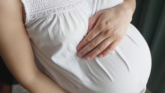 怀孕的女人感觉快乐期待母亲抱着婴儿在怀孕的肚子视频素材