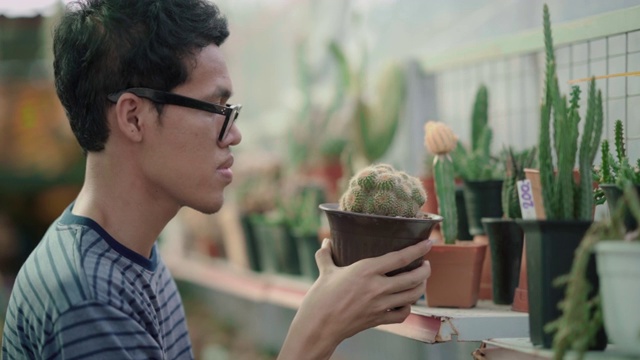 一个年轻人在花店选了一株植物视频素材