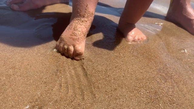 光着脚的婴儿脚趾在海滩上感受水和沙子视频素材