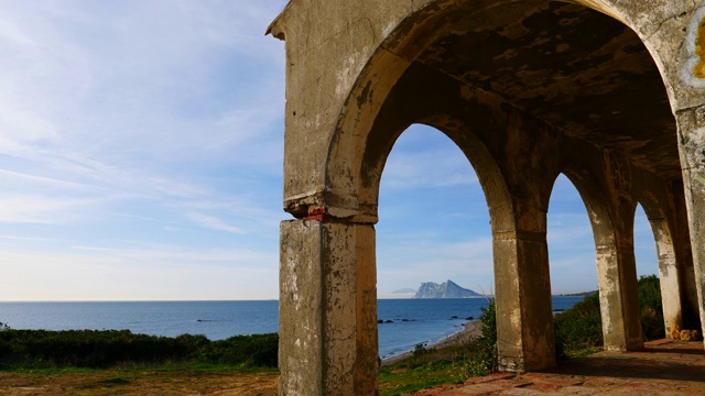 西班牙海岸线。海岸上的古老拱形建筑和地平线上的直布罗陀岩石。从托雷卡博尼拉海滩，蓬塔马拉，西班牙安达卢西亚视频素材