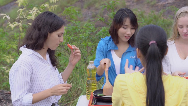 快乐的和一群朋友在夏天野餐与烹饪食物，团体女子享受和乐趣露营旅行冒险和早餐休闲一起在假期，背包旅行在假期。视频素材