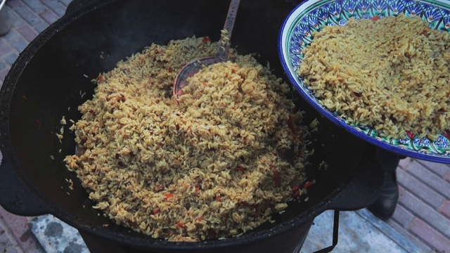 乌兹别克民族菜肴肉饭，肉饭，plov，米饭和肉放在大锅里。拿出大盘子，大锅里的胡萝卜着火了视频素材