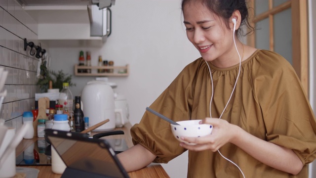 亚洲女性，作为自由职业者在家工作，进行电话会议，在厨房里讨论项目。视频素材