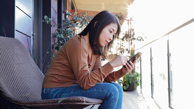 年轻女子在阳台上使用智能手机视频素材