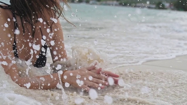 那个女孩躺在热带海滩的波浪中。视频素材