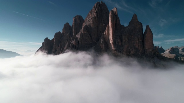 一架无人机从云层上方开始拍摄，显示一座山峰，然后飞向云层。意大利Dolomites, Tre Cime Di Lavaredo视频素材