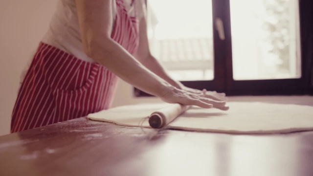 厨房里穿着红围裙的女人正在揉面视频素材