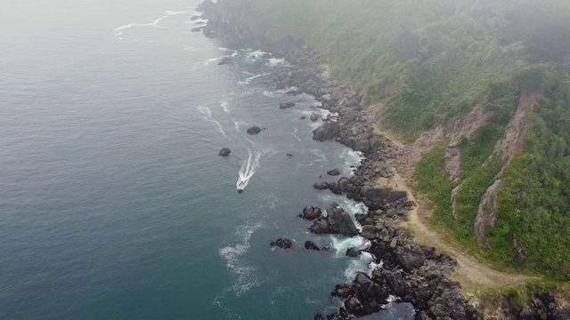 无人机拍摄的高速摩托艇沿着岩石海岸行驶视频素材