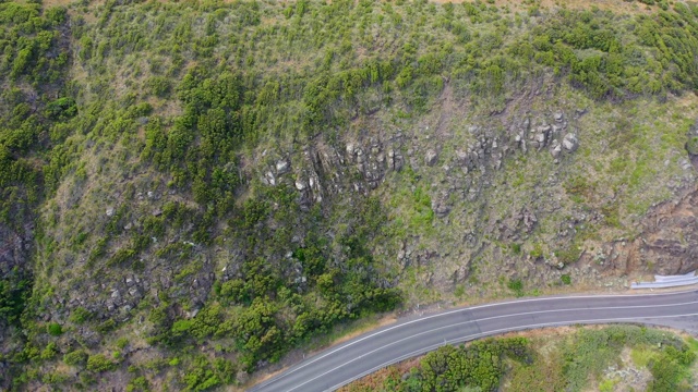 空中倾斜拍摄的道路与车辆在悬崖上在阳光明媚的一天，无人机飞过绿色植物-大洋路，澳大利亚视频素材