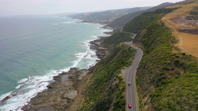 航拍的车辆在道路上的山悬崖由海上，无人机飞在海浪拍打海岸线对天空-大洋路，澳大利亚视频素材