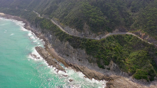 空中摇摄的车辆和人的道路上的悬崖由海上，无人机飞过绿色的山脉在阳光灿烂的一天-大洋路，澳大利亚视频素材